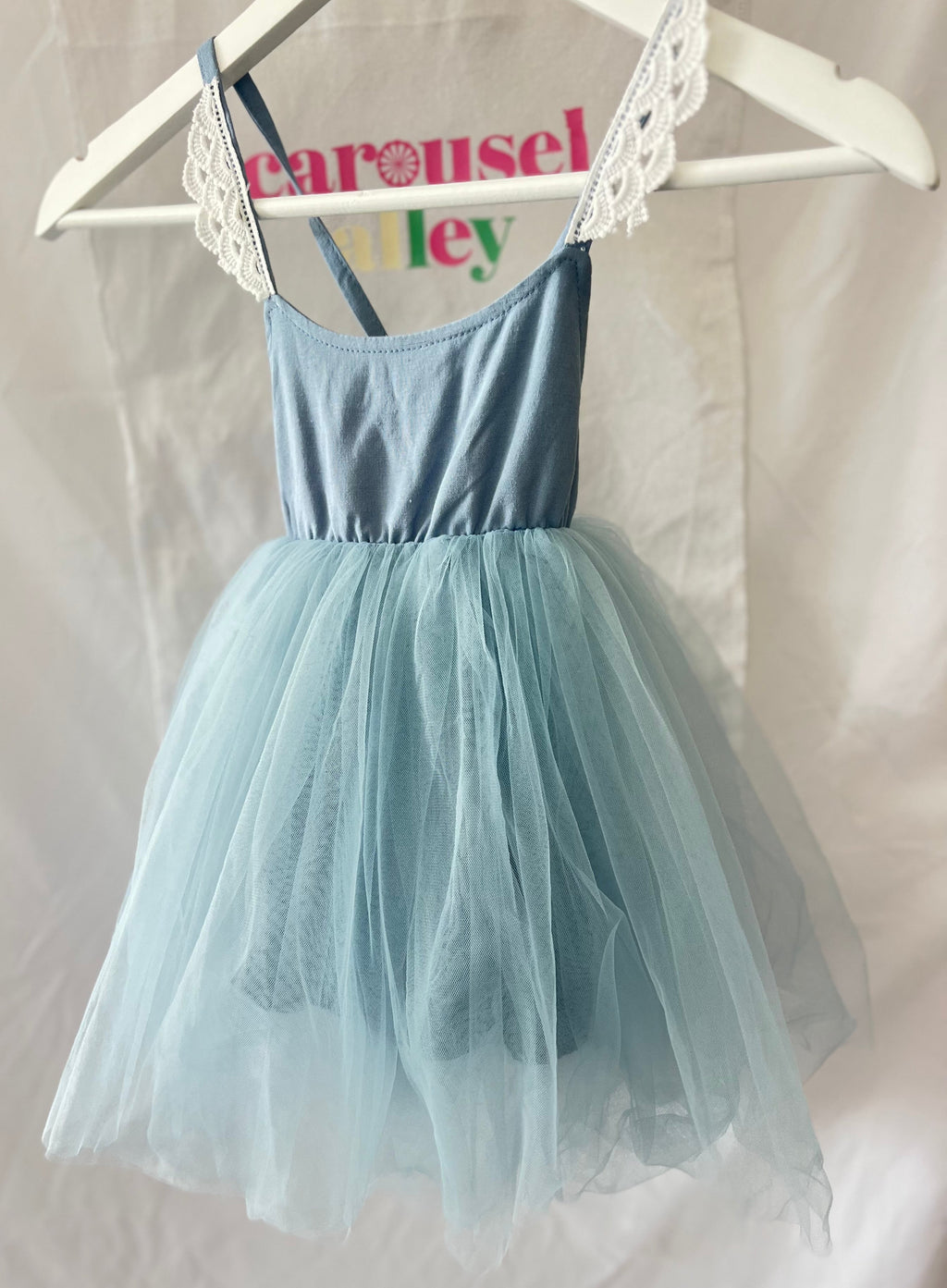 Light blue dress with tulle skirt on a hanger against a white background